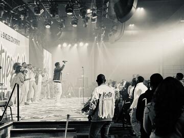 Black and white photo taken from the side of the stage where performer greets crowd