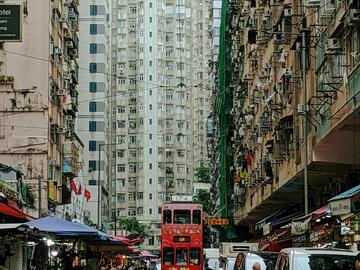 Red tram gliding away from the camera amongst sand-coloured buildings
