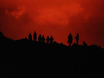 Silhouette of people on a ridgeline with a red glow in the background