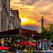 Bubbles floating through the sky during a sunset on a crowded summer city street