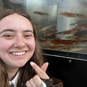Student posing in front of a fish tank