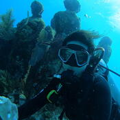 Student scuba diving in underwater with statues and plants 