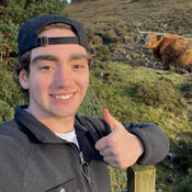 Student posing with a highland cow