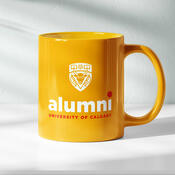 A yellow mug with the UCalgary Alumni logo