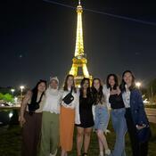 Selfie of a group of students in front of the Eiffel Tower, lit up at night