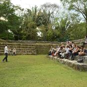 A class of students sitting on ancient stone steps, with an instructor speaking to them from the grass below