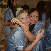 Two students in blue t-shirts smiling and hugging