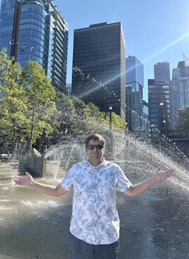 Student standing in a spray park under the mist