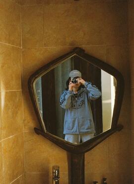 Student taking a photo of themselves in a small bathroom mirror