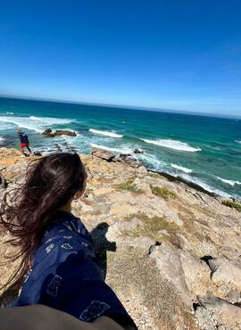 Photo of student gazing out at the cliffside ocean
