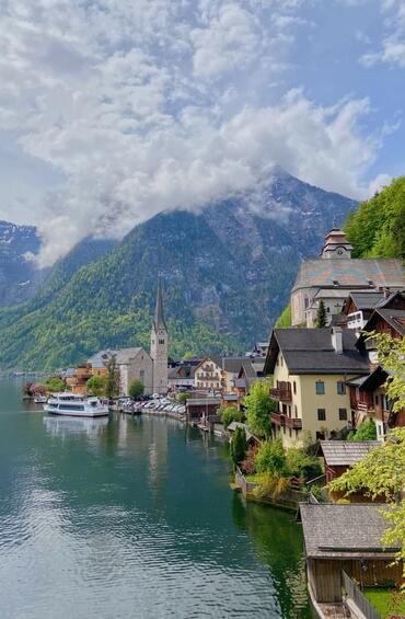 Overlooking a harbour with elegant architecture, a ship, and a misty mountain in the background