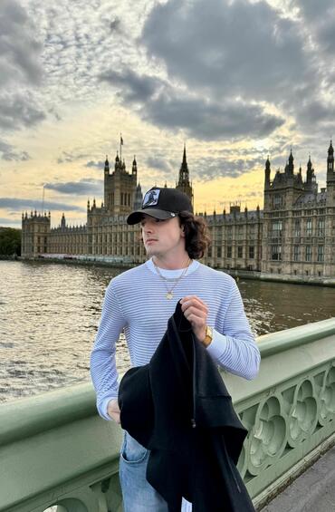 Student posing on a bridge with a London monument in the background