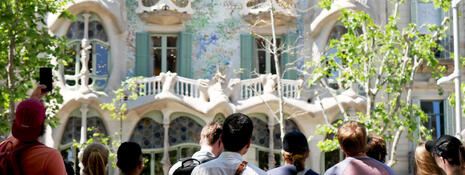 Looking over the heads of a class of students towards a castle wall with unique balcony carvings