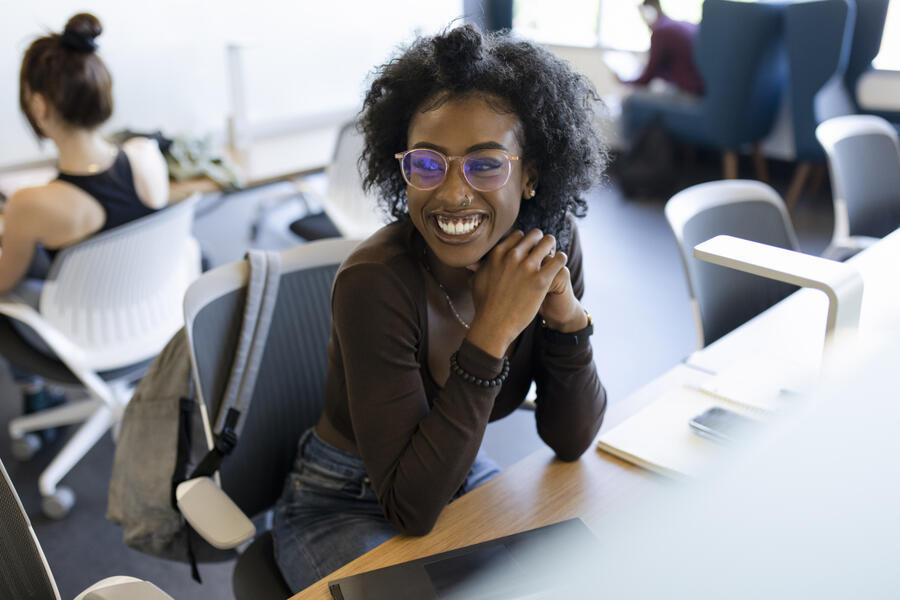 young black woman sitting and smiling in a communal office space