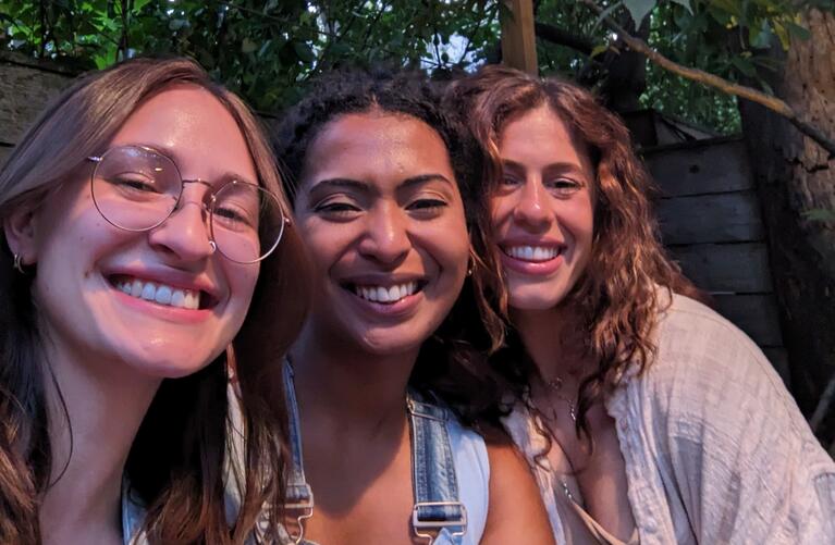 Joelle Hass and friends smiling outside under a tree.