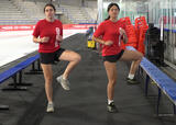 Two athletes performing open/close the gate exercise near a hockey rink