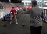 Athlete performing a quick feet reaction drill directed by their coach in an ice hockey arena