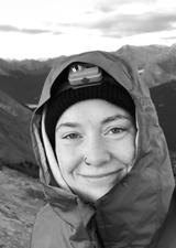 A young woman on the side of a mountain wearing a hood