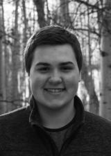 Kade Damant wearing a sweater standing in front of aspen or silver birch trees