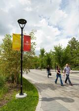 A couple of people are seen walking outside on campus during the summer months. 