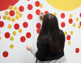 Woman writing a note on an activation station pop-up.