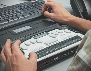 Close up of hands using an assistive keyboard on a computer