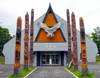 A Japanese Indigenous building with a large eagle on the front and totems on either side