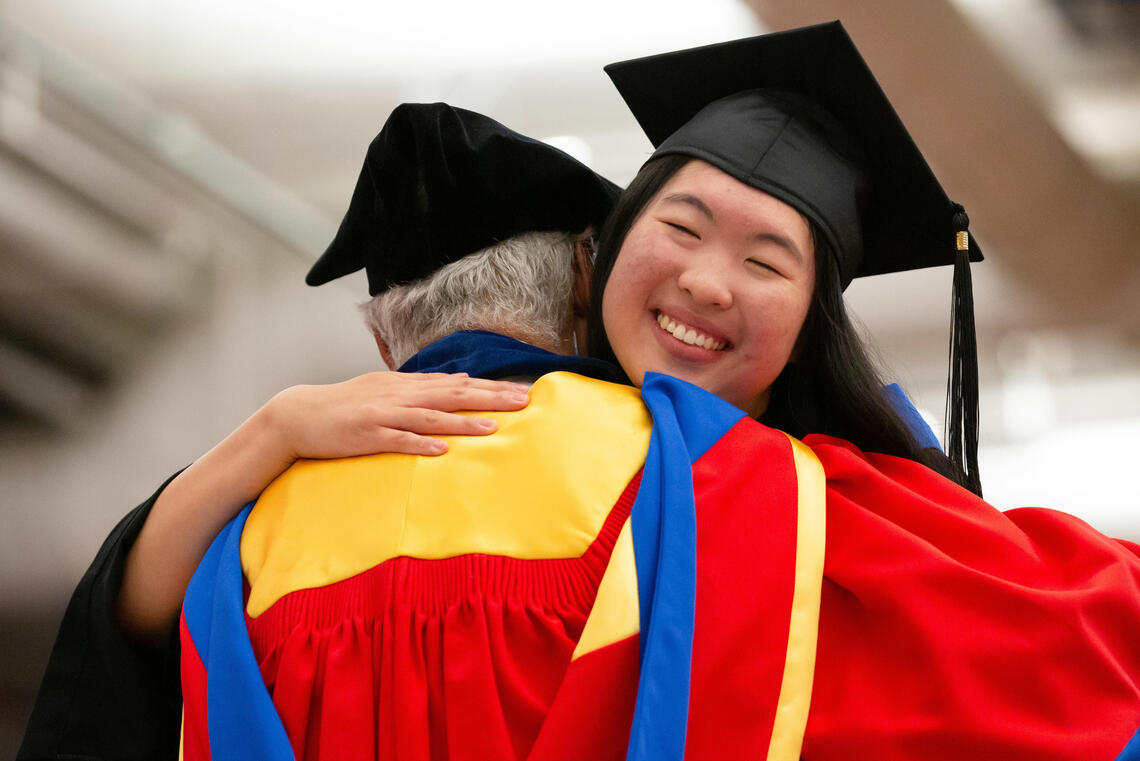 Two people in convocation regalia hugging