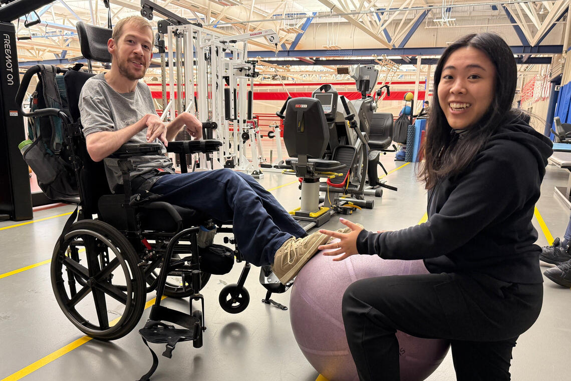 A person in a wheelchair works with a trainer in a physical rehab center
