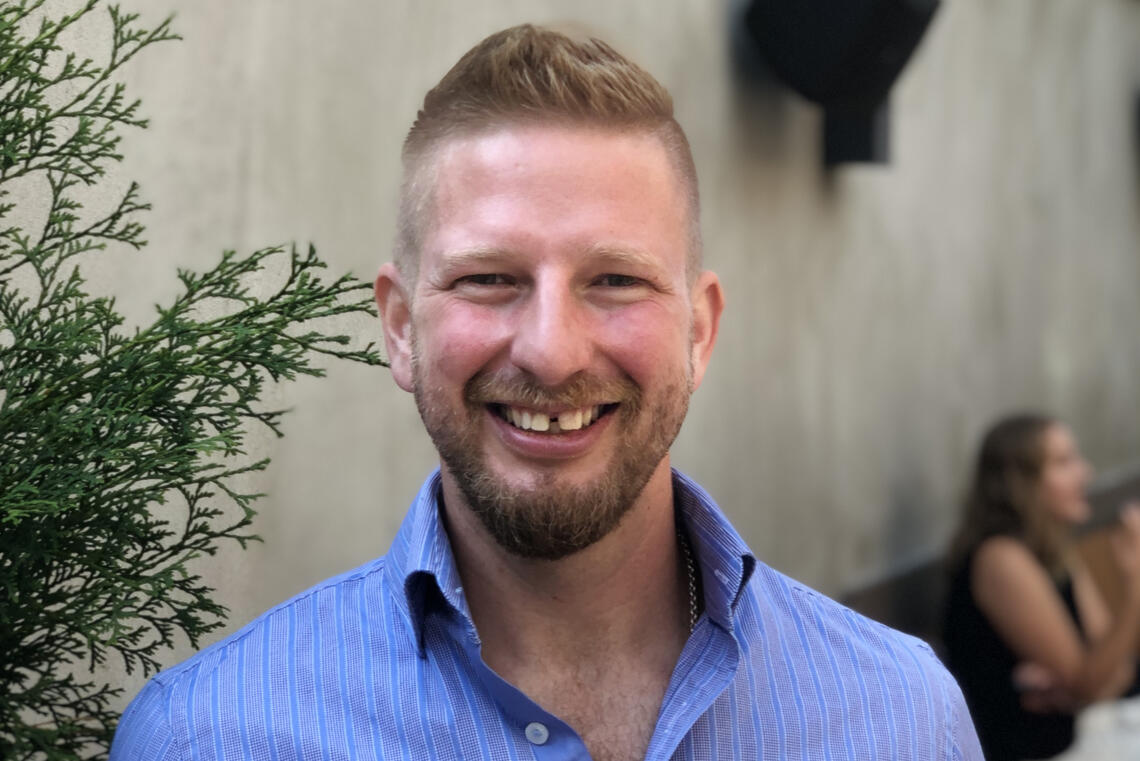 A man with short hair smiles at the camera