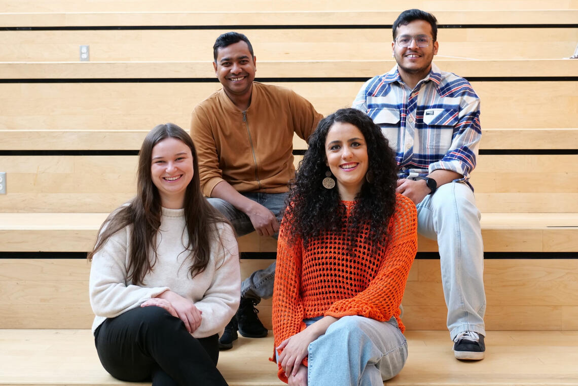 A group of four students sitting on steps