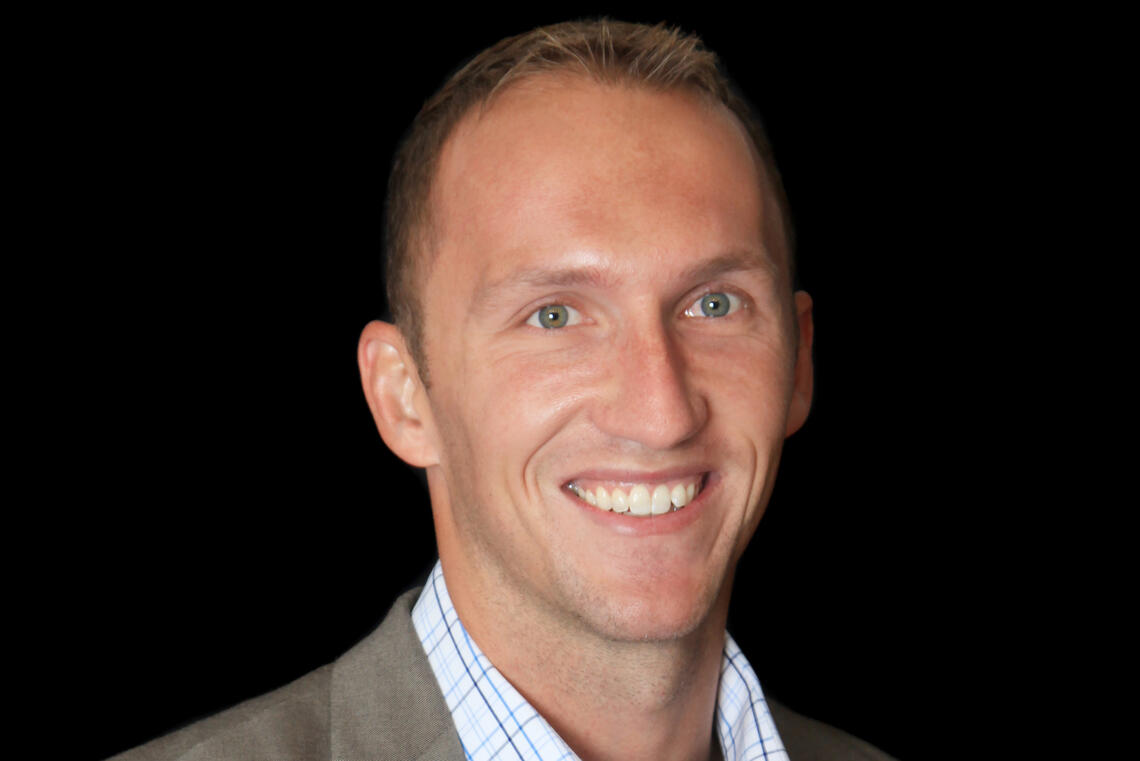 A man with short hair smiles at the camera