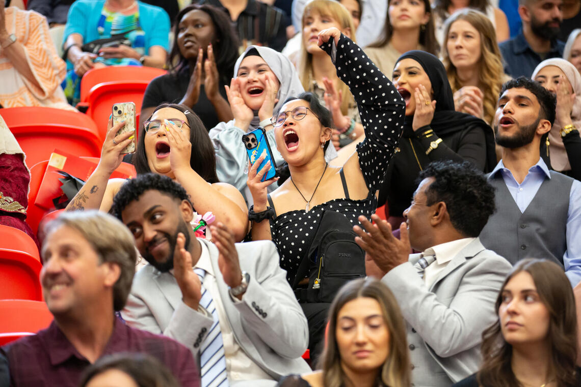 A group of people cheer on graduates
