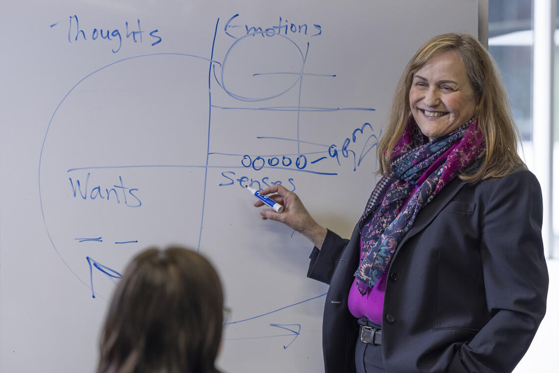 A woman stands at a whiteboard