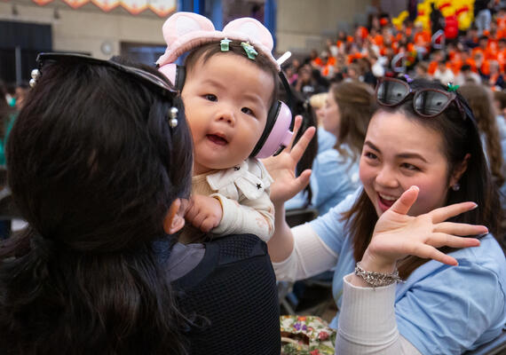 A baby wearing ear protection and a student looking at her