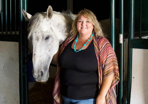 A woman stands next to a horse